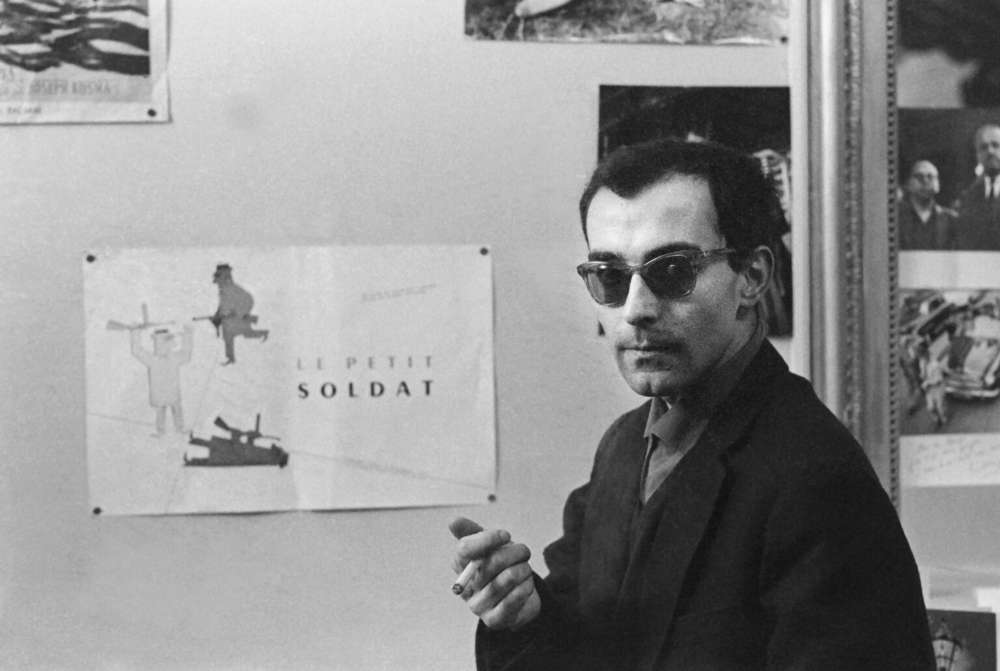 Le réalisateur français Jean-Luc Godard devant une affichette "Le Petit soldat" en 1963, Paris.