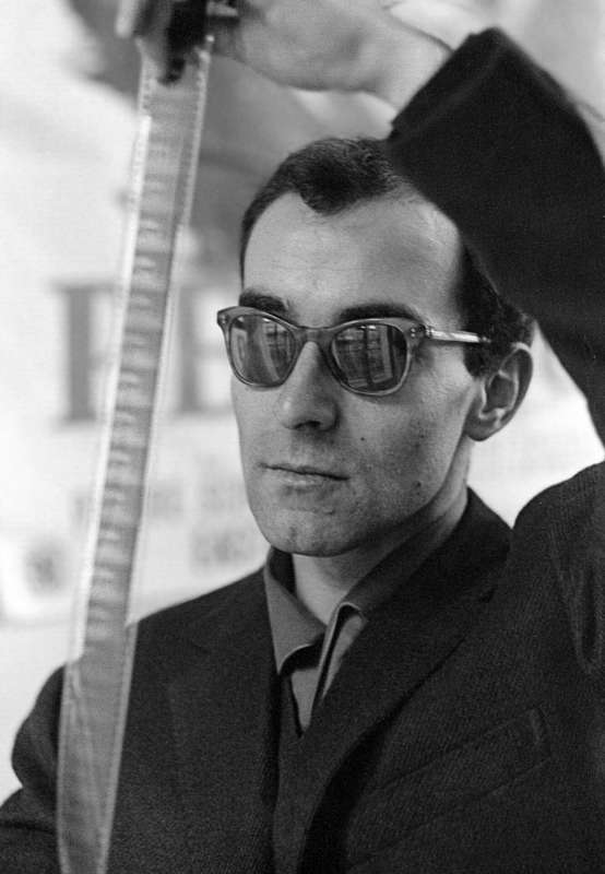 Le réalisateur français Jean-Luc Godard regardant une pélllicule de film en 1963.
